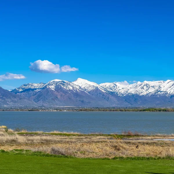 Marco Marco Cuadrado Vista panorámica de un lago con hierbas marrones y campo soleado en primer plano —  Fotos de Stock