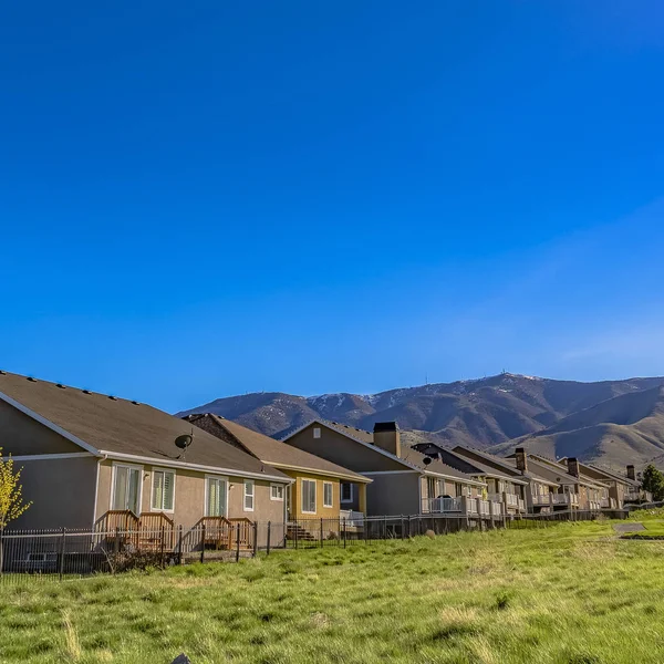 Casas cuadradas en un vasto campo de hierba con una montaña imponente en la distancia — Foto de Stock