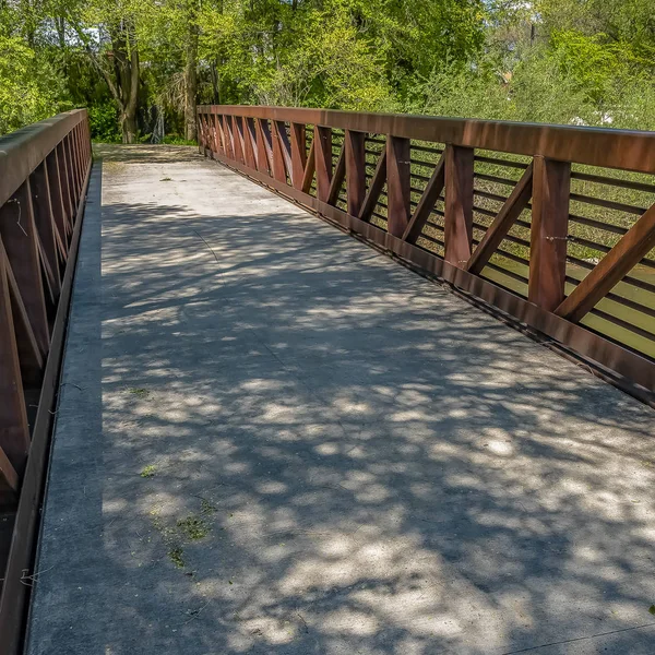 Jembatan Frame Square dengan pagar coklat menghadap ke sungai dan banyak pohon . — Stok Foto