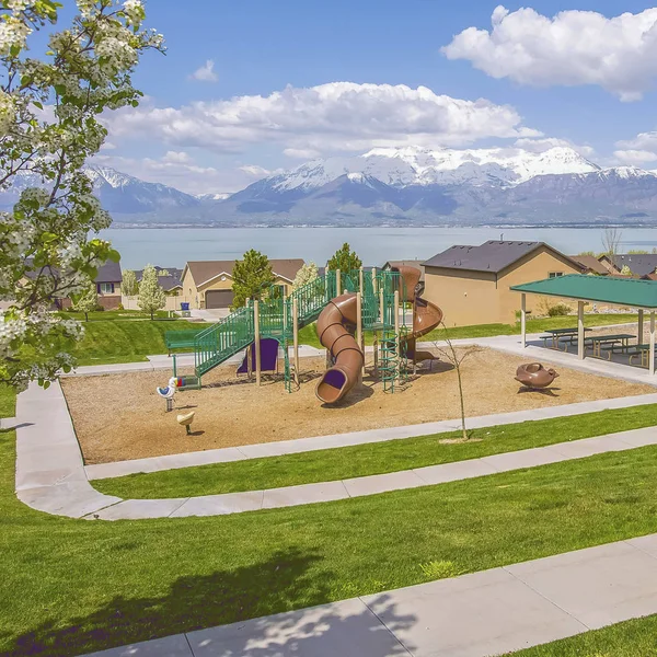 Frame Square Área de juegos y picnic con casas lago y montaña en el fondo — Foto de Stock