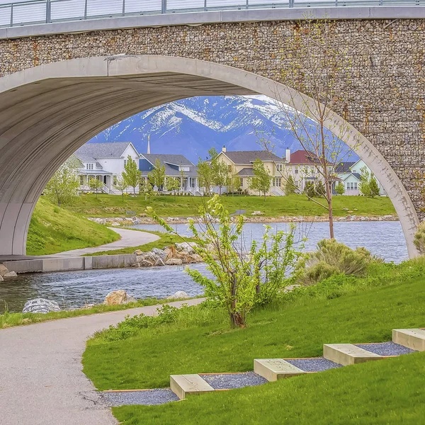 Frame Square Ponte ad arco su un lago scintillante con vista sulle case e sulle montagne innevate — Foto Stock