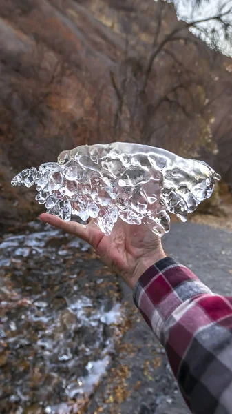 険しい山に対して輝く半透明の氷の塊を保持するパノラマフレーム男 — ストック写真