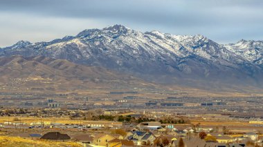 Geniş vadide evlerde yükselen karla kaplı dağın Panoraması