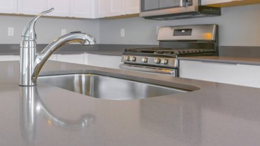 Panorama yakın yukarı musluk ile parlak bir tezgah ve modern bir mutfak içinde lavabo