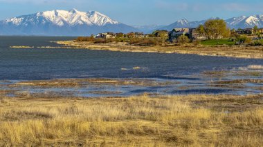 Dağ ve mavi gökyüzüne karşı çimenli kıyı ve ışıltılı su ile Panorama Gölü