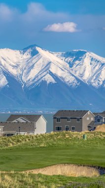Geniş bir göl ve karla kaplı dağa bakan evler ile Panorama Grassy Tepesi