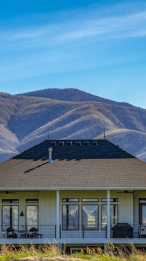 Panorama çerçevesi güneşli bir günde dağ ve mavi gökyüzüne karşı şık bir evin dış görünümü