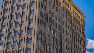 Panorama çerçevesi cam pencerelere yansıyan bulutlu mavi gökyüzü ile bir binanın dış