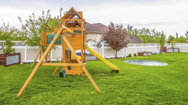 Bir evin geniş arka bahçesinde Panorama Playground ekipmanları ve küçük havuz