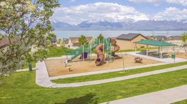 Arka planda evler göl ve dağ ile Panorama Playground ve piknik alanı