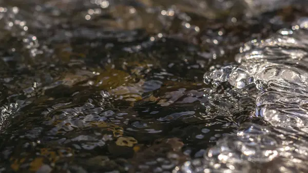 Marco panorámico Primer plano de un arroyo con agua congelada translúcida sobre rocas oscuras —  Fotos de Stock