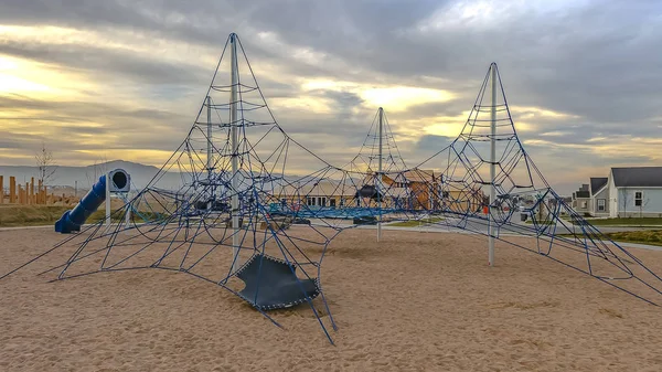 Panorama frame Rope climbing frame and tunnels at a playground under cloudy sky at sunset