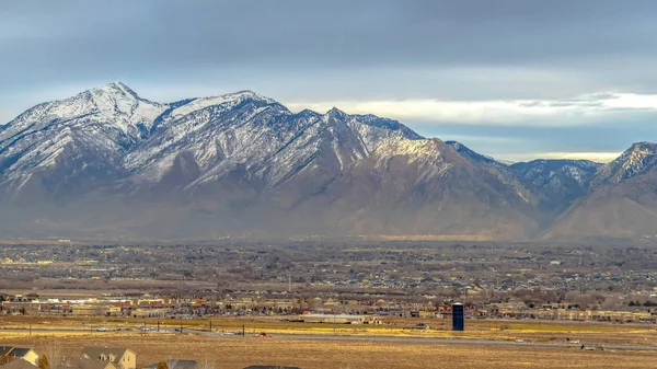 Panorama Panorama d'une montagne enneigée dominant les maisons dans la vaste vallée — Photo