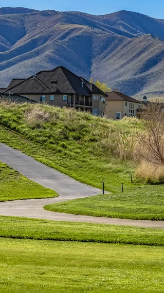 Panorama Panorama of a road curving through a hill covered with grasses on a sunny day — Stock Photo, Image