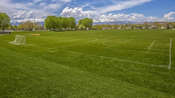 Panorama marco Amplio campo de deportes con red de gol de fútbol y gradas de béisbol detrás de una valla —  Fotos de Stock