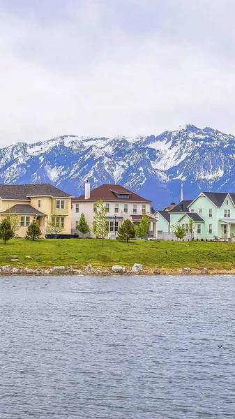 Panorama çerçevesi yemyeşil çimenli kıyı ile parlak sakin gölün önünde güzel evler