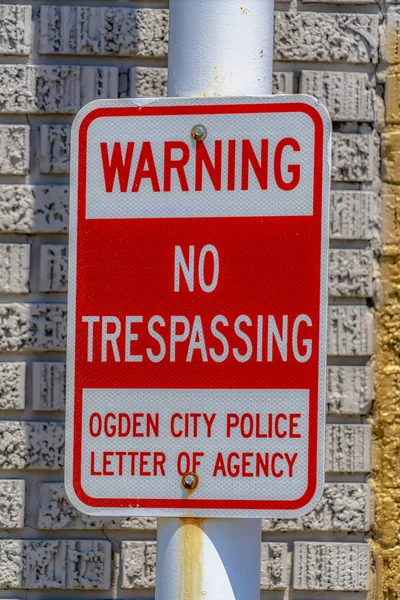 Warning No Trespassing sign against a metal pole and rough brick wall — Stock Photo, Image