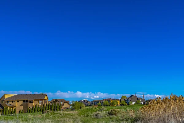 Casas em um vasto terreno gramado com fundo rico céu azul em um dia ensolarado — Fotografia de Stock