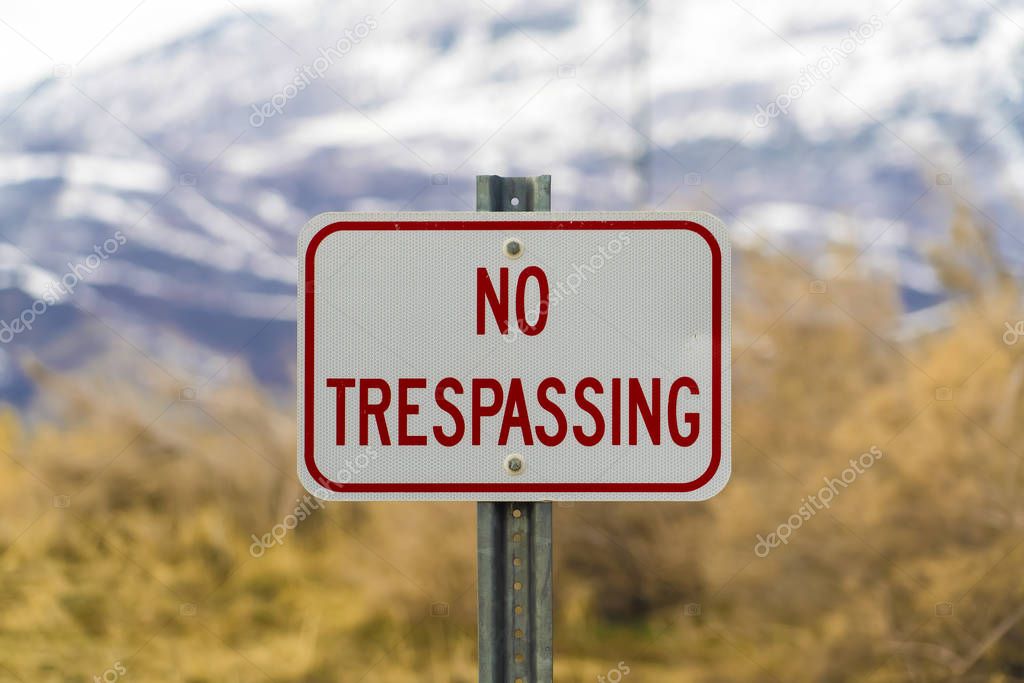 Close up of white sign board with the words No Trespasing painted in red color