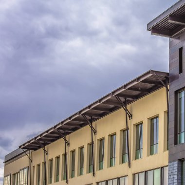 Bulutlu gri bulutlar ile kaplı gökyüzüne karşı düz bir çatı ile kare bina dış