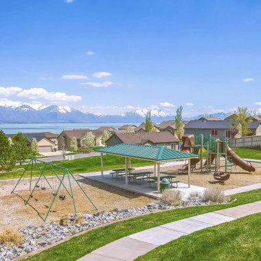 Bir gölün yakınında bir mahallede oyun alanı ve piknik alanı ile kare evler ve Park