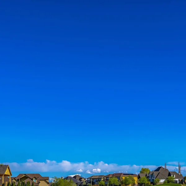 Vierkante frame huizen op een uitgestrekt grasachtig terrein met rijke blauwe hemel achtergrond op een zonnige dag — Stockfoto