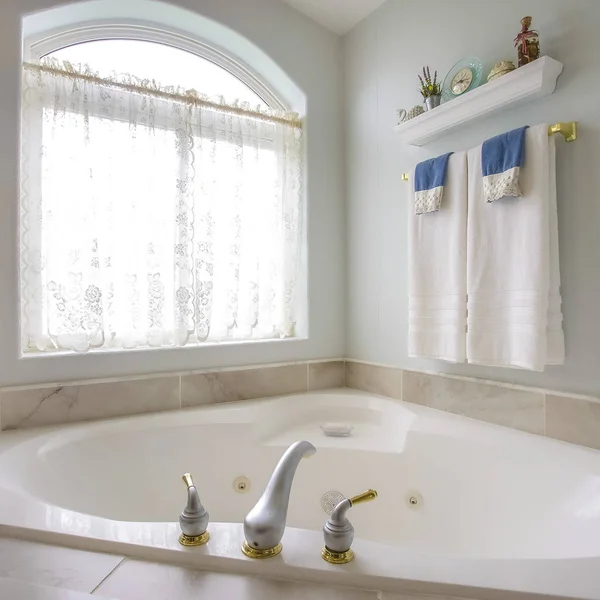 Квадратная рама Ванная комната с золотым и серебряным краном рядом с арочным окном с занавесом — стоковое фото