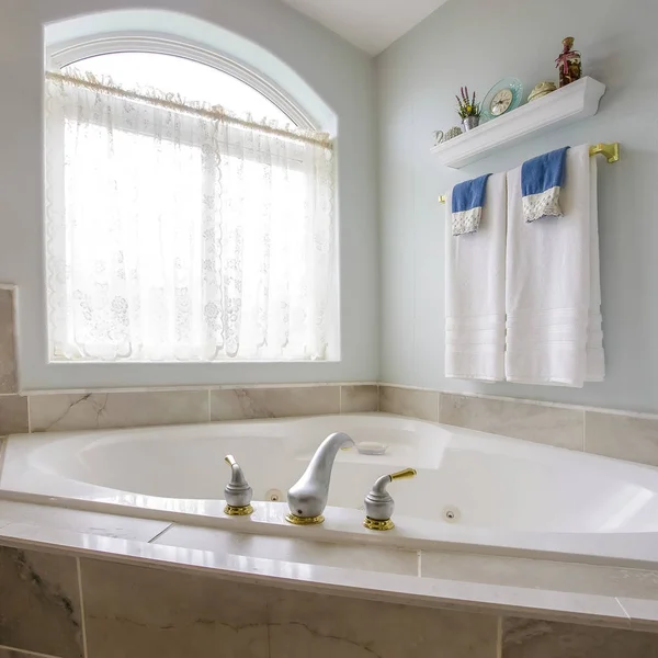 Square frame Built in bathtub at the corner of a bathroom with a large arched window — Stock Photo, Image