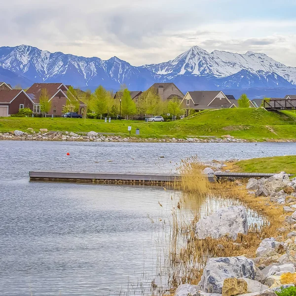 Square Wooden deck on a scenic lake with rocks and bright green grasses on the shore