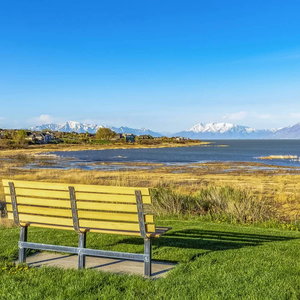 Marco cuadrado Banco vacío con vistas a un lago y proyectando sombra en el campo en un día soleado —  Fotos de Stock