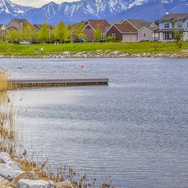 Square frame Wooden deck on a scenic lake with rocks and bright green grasses on the shore