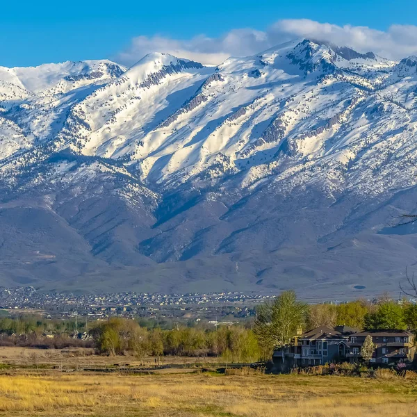 Quadratischer Rahmen markanter schneebedeckter Berg, der an einem sonnigen Tag unter blauem Himmel über dem Tal thront — Stockfoto