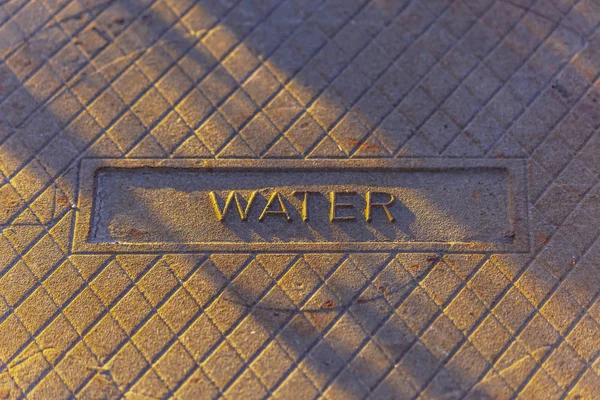 Agua estampada en la cubierta de un hoyo de hombre — Foto de Stock