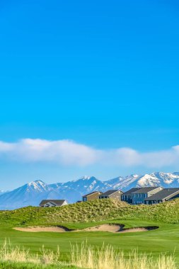 Karla kaplı dağa ve mavi gökyüzüne karşı bir tepede bulutlar ile Residences