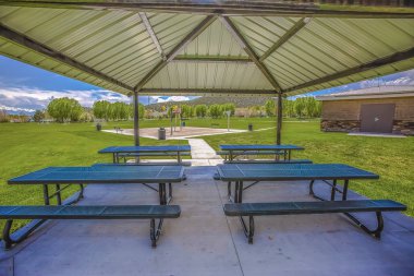 Yemyeşil otlar ve ağaçlarla çevrili bir köşkün içindeki açık beslenme alanı