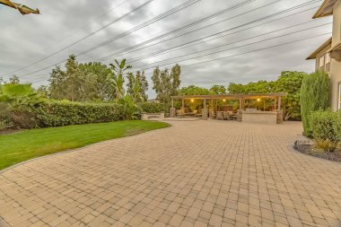 Bir pavyon altında yangın çukuru ve yemek alanı ile taş tuğla driveway ve veranda