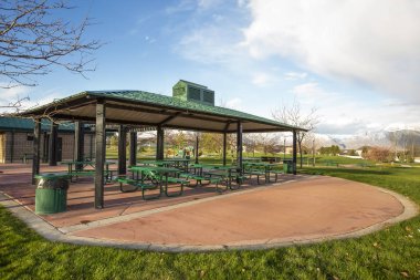 Bulutlu mavi gökyüzü altında doğal bir parkta kapalı piknik alanı