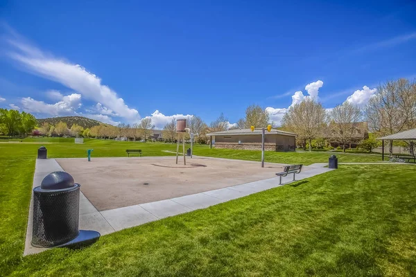 Parque en un campo exuberante con vistas a los árboles de montaña y edificios contra el cielo azul — Foto de Stock