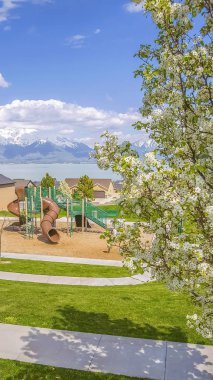 Bulutlu mavi gökyüzü altında göl ve dağa karşı Dikey Oyun alanı ve yerleşim alanı