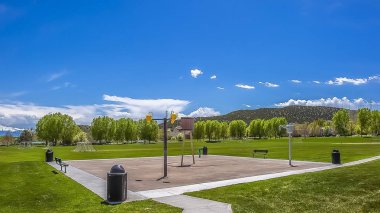 Bulutlar ile geniş mavi gökyüzü altında yemyeşil bir çimenli alanın ortasında Panorama çerçeve Park