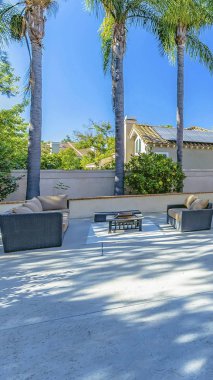 Yemyeşil bitkiler ve palmiye ağaçları ile bir evin geniş veranda üzerinde Dikey çerçeve Oturma alanı