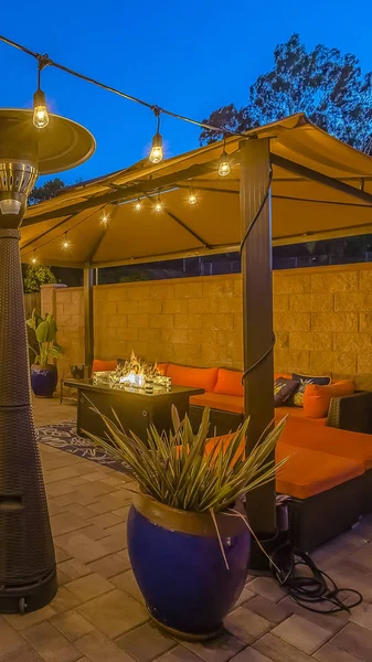 Vertical Stone brick patio of a home illuminated with string lights and lamp posts