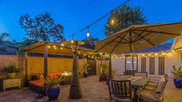 Panorama frame Stone patio with seating area under a gazebo and dining area under an umbrella