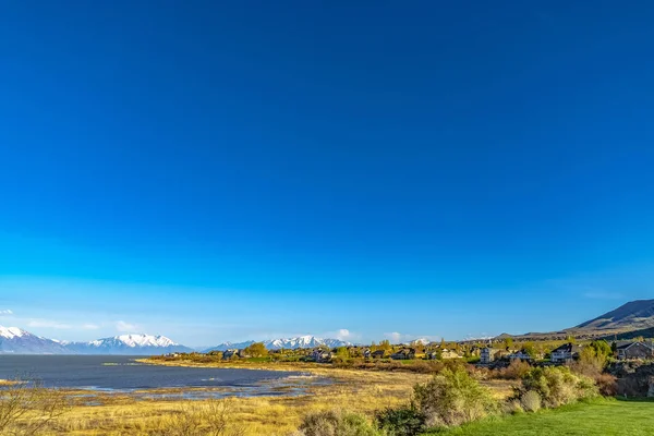 Panoramatický výhled na jezero a zasněžené hory pod temně modrou oblohou — Stock fotografie