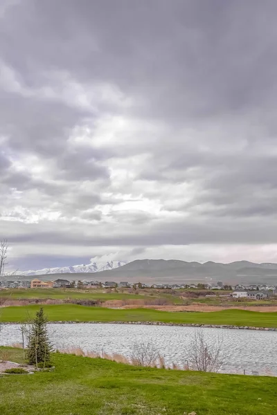 Lago prateado com vista para montanhas distantes sob o céu cheio de nuvens cinzas — Fotografia de Stock