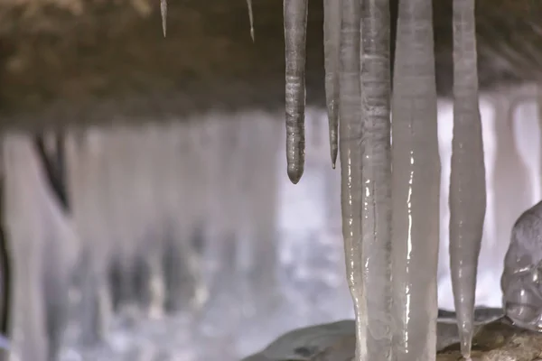 Nahaufnahme von glatten und glänzenden Eiszapfen unter einer Brücke im Winter — Stockfoto
