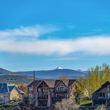 Dağlar ve bulutlu mavi gökyüzü arka plan ile güzel evlerin Kare Cephe