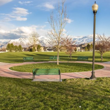 Ağaçlar ve lamba direkleri ile bir park üzerinde dairesel bir yol etrafında Kare Yeşil banklar