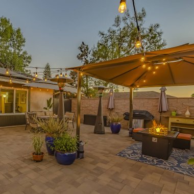 Kapalı bir oturma ve yemek alanı üzerinde ışıklar dize ile Kare çerçeve Cozy taş veranda
