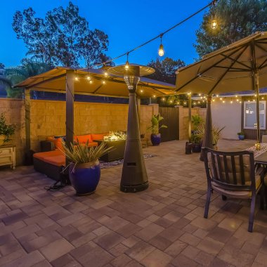 Bir çardak altında oturma alanı ve bir şemsiye altında yemek alanı ile Square Stone veranda